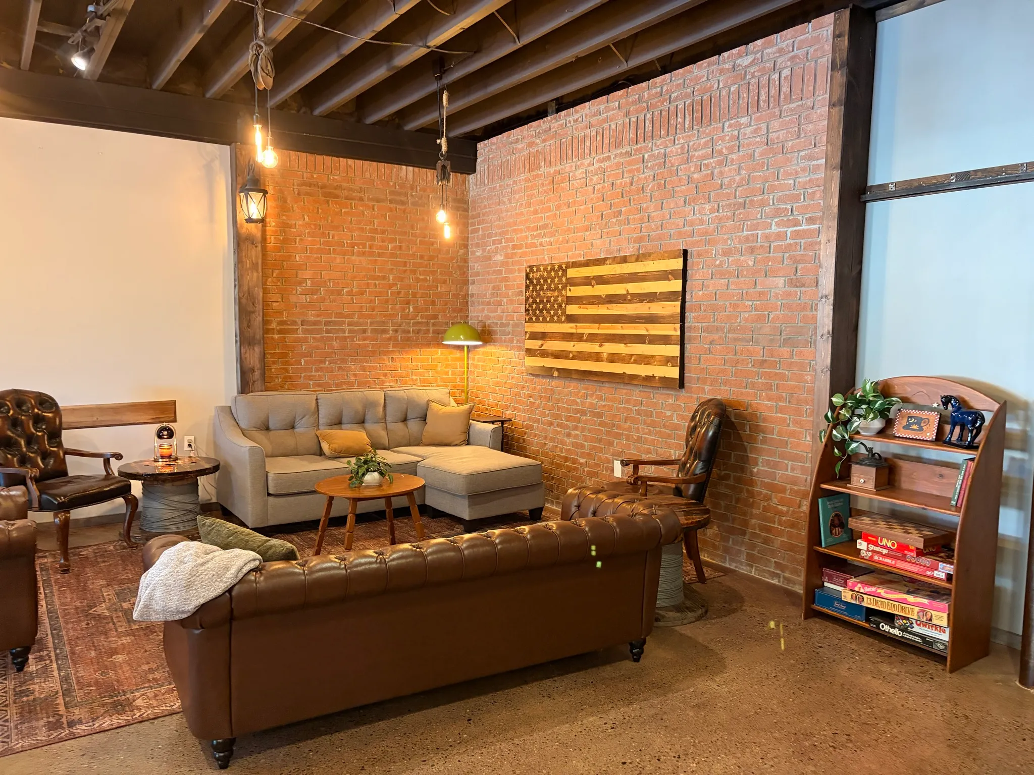 A corner of The Room with a sectional sofa, leather armchairs and a shelf of board games
